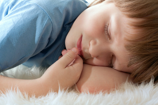 Cute boy sleeping on white fur. Sleep well. - Foto, imagen