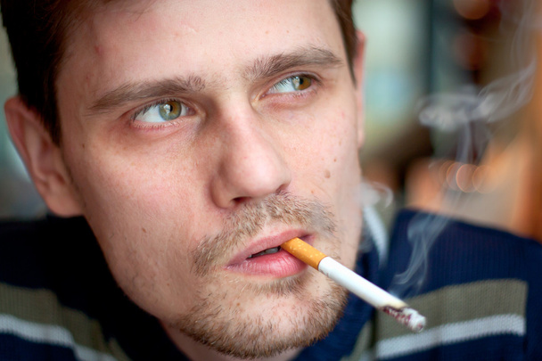 Мужчина средних лет курит сигарету в баре. Сосредоточься на глазах
. - Фото, изображение