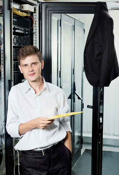 Инженер в костюме стоит в дата-центре рядом с телекоммуникационным оборудованием хо
 - Фото, изображение