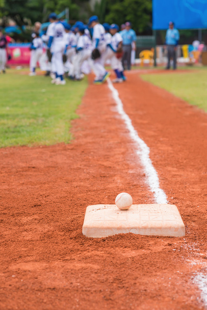 béisbol y base en el campo de béisbol con jugadores y jueces en el fondo
 - Foto, imagen