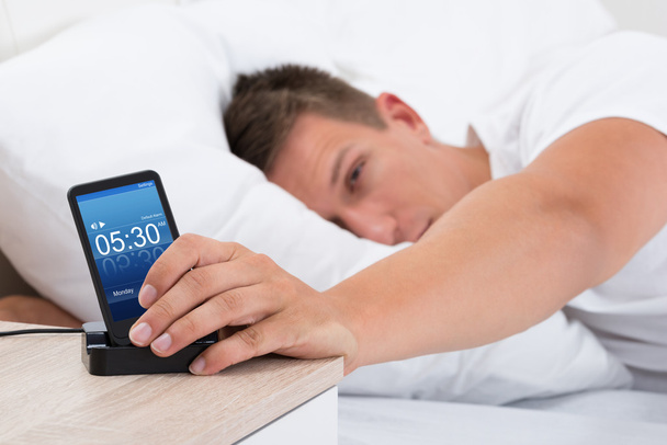 Man Snoozing Alarm Clock On Cell Phone - Foto, Bild
