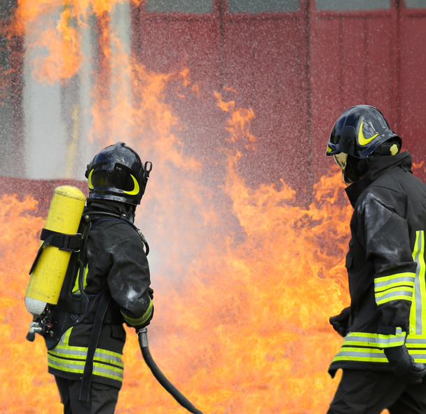 brandweerlieden met zuurstofflessen uit het vuur tijdens een training - Foto, afbeelding