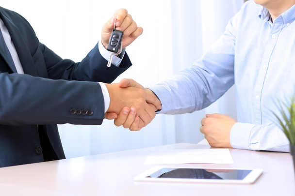 Car salesman handing over the keys for a new car to a young busi - Photo, Image