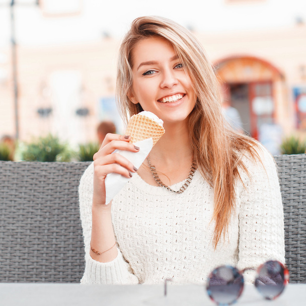 Smiling girl eating an ice-cream scoop in a waffle cone - Zdjęcie, obraz