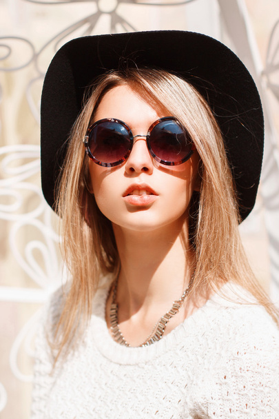 Portrait of a beautiful young girl in a black hat and round sunglasses on a sunny day. - Photo, Image