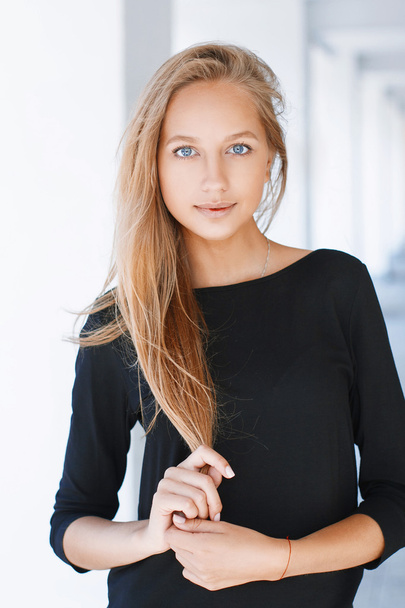 Beautiful woman with blue eyes in a black shirt on a light background - Foto, imagen