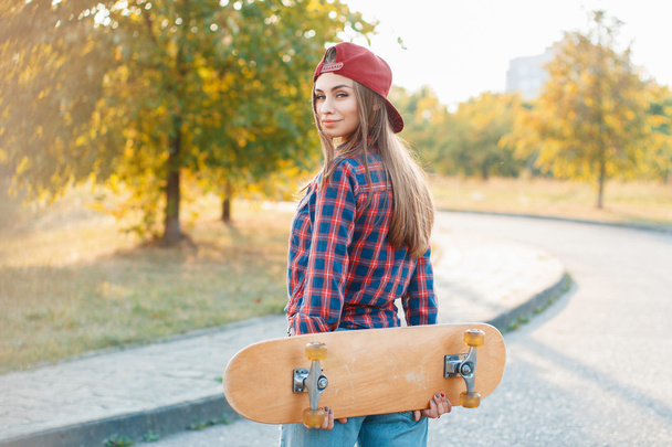 mooi en mode jong vrouw poseren met een skateboard - Foto, afbeelding