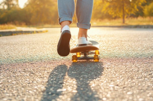 Skateboarding legs at skate park. Beautiful weather with the sunset. Woman moves forward - Φωτογραφία, εικόνα