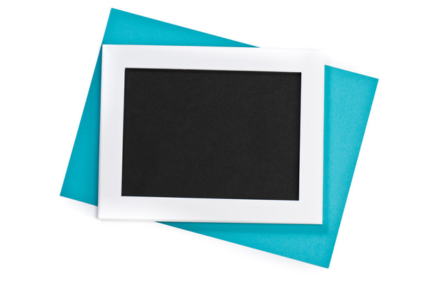 horizontal white photo frame with black field and blue paper under angle on white background isolated with real shadows - Φωτογραφία, εικόνα