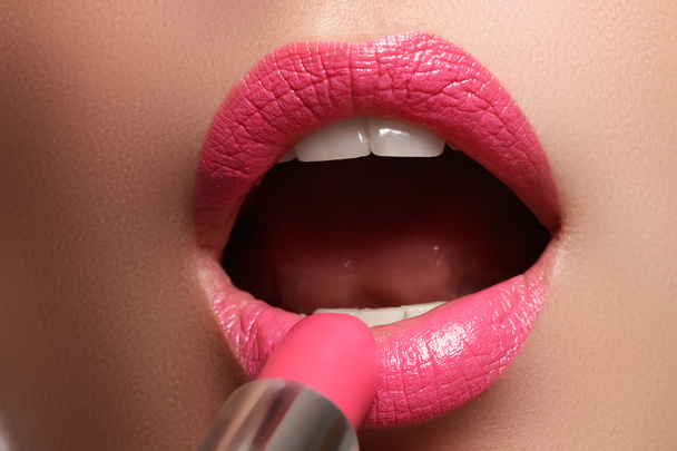 Женщина красила розовые губы. Косметика для губ. Идеальная кожа, полные губы. Ретро макияж. Профессиональный визажист наносит сексуальный макияж губ. Мода макияж
 - Фото, изображение