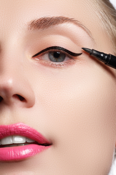 Beautiful woman with bright make up eye with sexy black liner makeup. Fashion arrow shape. Chic evening make-up. Makeup beauty with brush eye liner on pretty woman face - 写真・画像