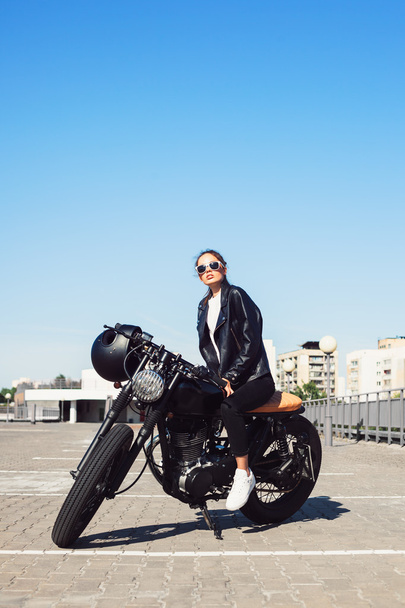 Biker girl sitting on vintage custom motorcycle - Фото, изображение