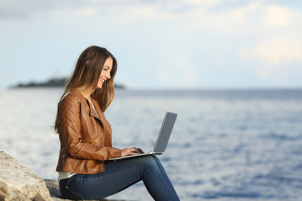 Self employed woman working with a laptop on the beach - Foto, Imagen