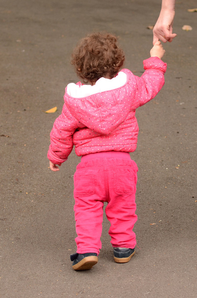 Lapsi pitää kädestä ja kävelee puistossa äitinsä kanssa.
 - Valokuva, kuva