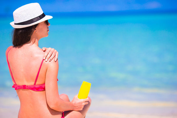 Красива молода жінка тримає сонячний крем, що лежить на тропічному пляжі
 - Фото, зображення