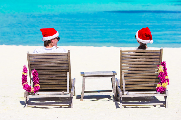 Young couple in Santa hats relaxing on beach during Christmas vacation - Photo, Image
