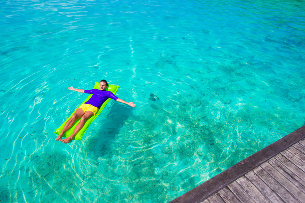 Jovem homem feliz relaxando no colchão inflável no mar
 - Foto, Imagem
