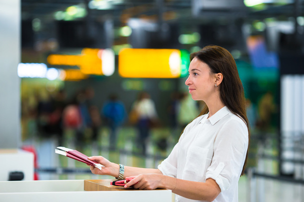 Женщина с паспортами и посадочными талонами на стойке регистрации в аэропорту
 - Фото, изображение