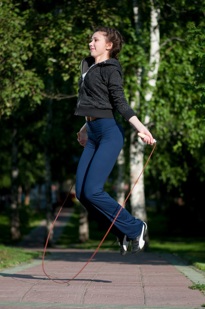 Jumping woman with skipping rope at park - 写真・画像