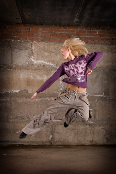 Beautiful hip hop girl dancing over grey brick wall - Foto, afbeelding