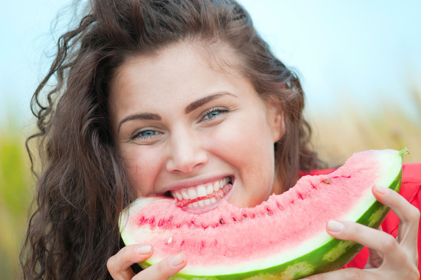 Woman in wheat field eating watermelon. Picnic. - Фото, изображение