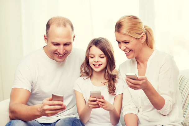 parents and little girl with smartphones at home - 写真・画像