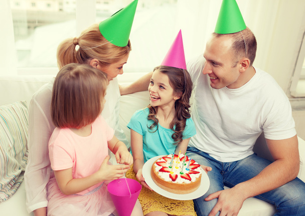 smiling family with two kids in hats with cake - Photo, image