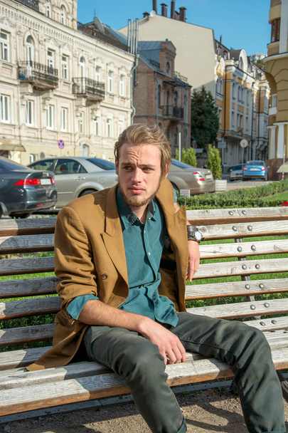 Un giovane seduto su una panchina - Foto, immagini