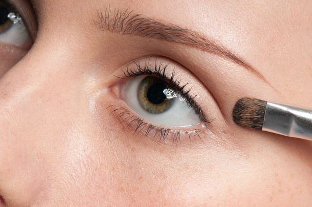 Frau trägt kosmetischen Pinsel auf Augenpartie auf - Foto, Bild