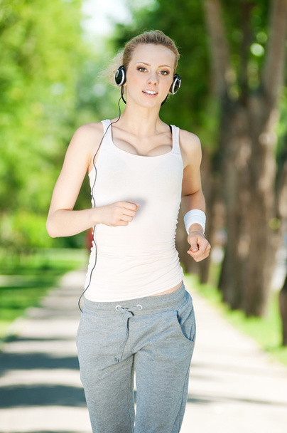 Young woman running in green park - Valokuva, kuva