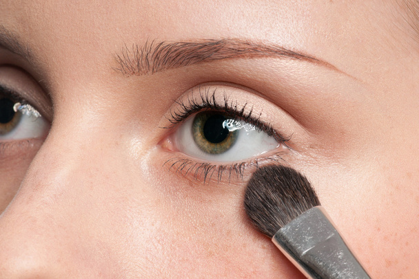Woman applying cosmetic paint brush on eye zone - Foto, afbeelding
