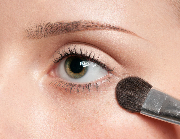 Mulher aplicando pincel de tinta cosmética na zona dos olhos
 - Foto, Imagem