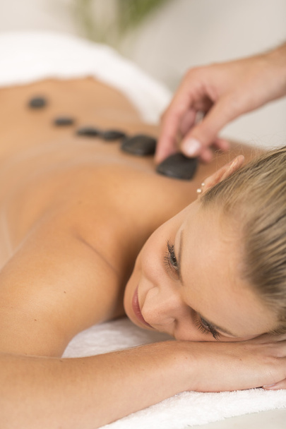 Giovane donna ottenere massaggio di pietra calda nel salone spa - Foto, immagini