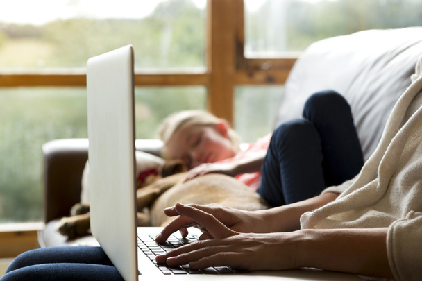 Mother using laptop whilst daughter sleeps - Foto, Bild