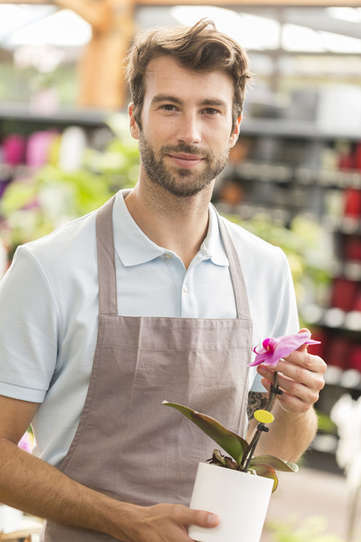 Male florist holding a flower - Foto, imagen