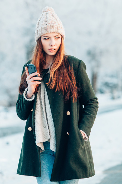 Young  woman smiling with smart phone and winter landscape . - Foto, imagen