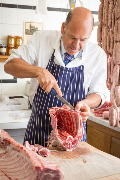 Butcher in shop butchering a rack of lamb - Photo, Image