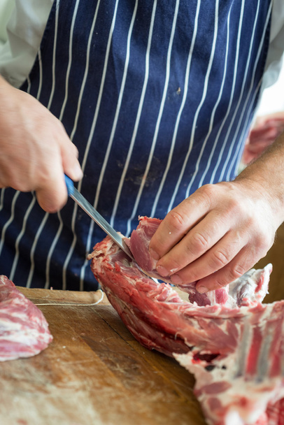 Slager trimmen gewricht van vlees - Foto, afbeelding