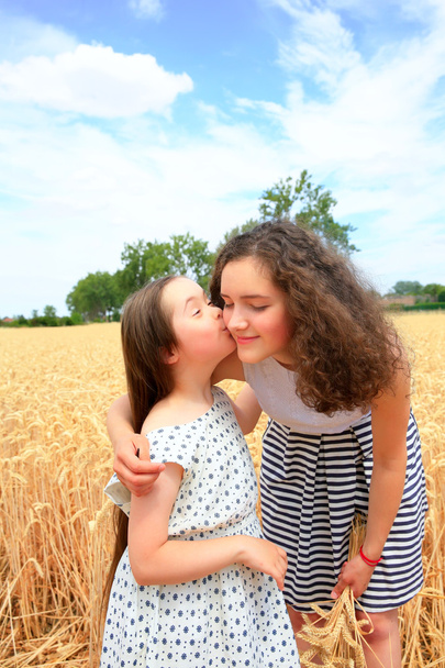 Szczęśliwych chwil rodzinnych - młode dziewczyny zabawy ln pole pszenicy - Zdjęcie, obraz