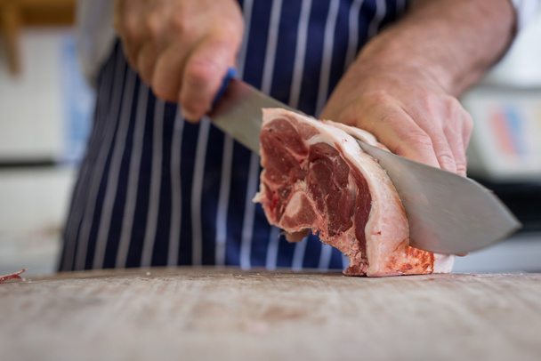 Close up of butcher carving raw lamb - Photo, Image