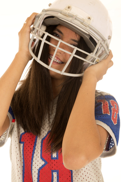 Teini-ikäinen tyttö yllään amerikkalainen jalkapallo kypärä hymyilee
 - Valokuva, kuva