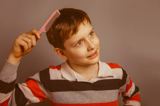 Ευρωπαϊκή εμφάνιση αγόρι δέκα ετών χτενίζει τα μαλλιά της σε ένα γκρι bac - Φωτογραφία, εικόνα