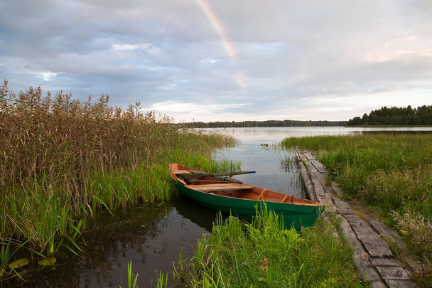 Літні краєвиди озера з дерев'яним човном і веселкою
 - Фото, зображення
