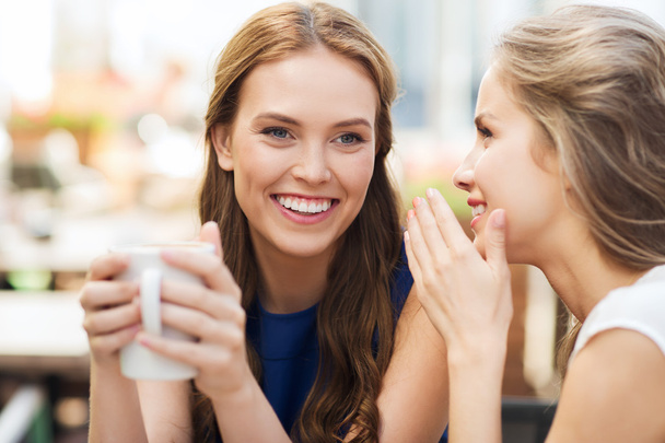 young women drinking coffee and talking at cafe - Photo, image