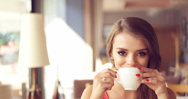 Uśmiechnięta młoda kobieta picia kawy w słoneczny Cafe - Zdjęcie, obraz