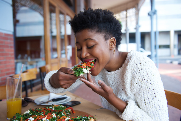 屋外レストランでピザを食べるアフリカ系アメリカ人の女性 - 写真・画像