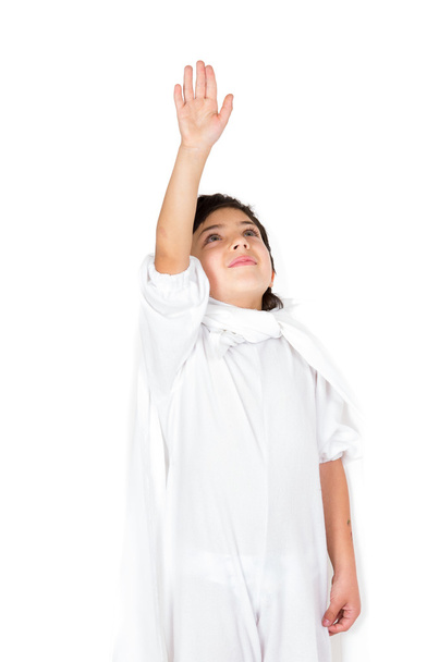 Small boy wearing all white clothing and dark hair holding right arm up to the sky as in flying - Foto, Imagen