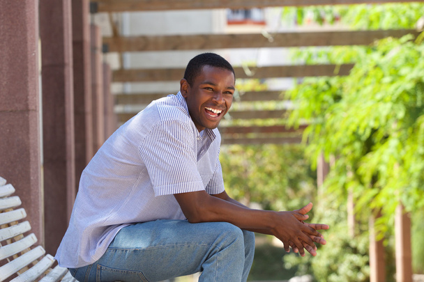 Young black man sitting outside laughing - Valokuva, kuva