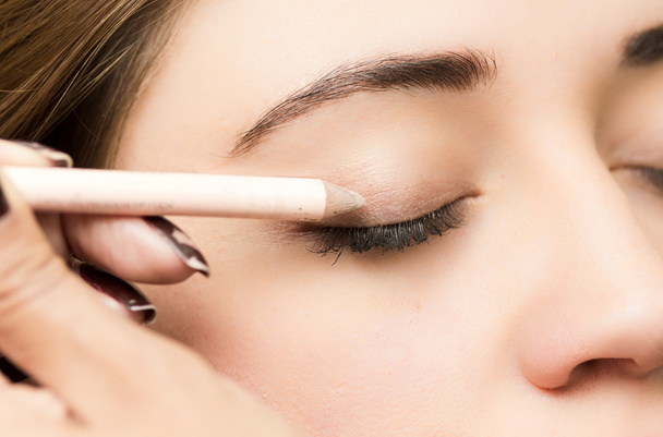 Closeup headshot brunette getting makeup treatment by professional stylist applying eyeliner - Foto, immagini