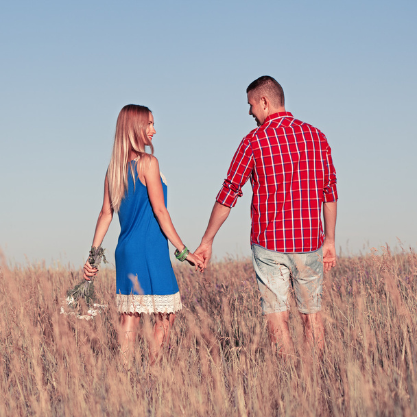 Rakkaustarina. Kaunis nuori pari kävelee niityllä, ulkona
 - Valokuva, kuva